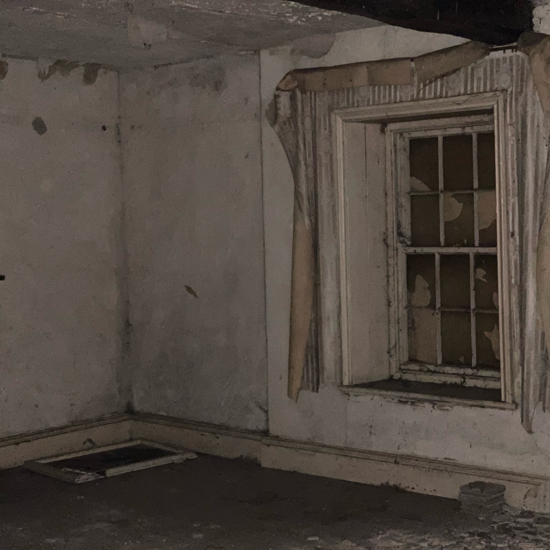 Dilapidated room interior with damaged walls and window in abandoned house.