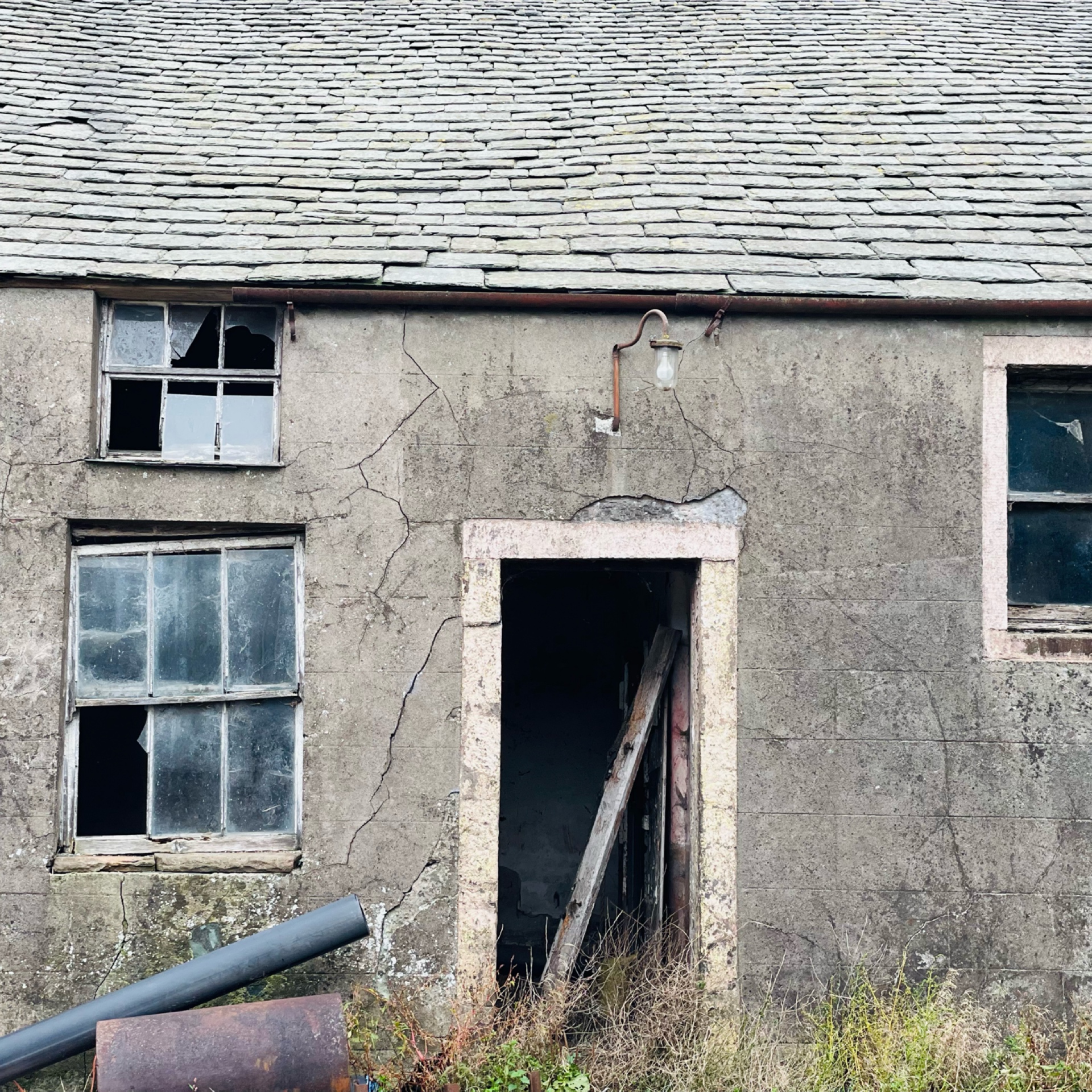Traditional Buttermere slate roof tiles on weathered abandoned farmhouse exterior.