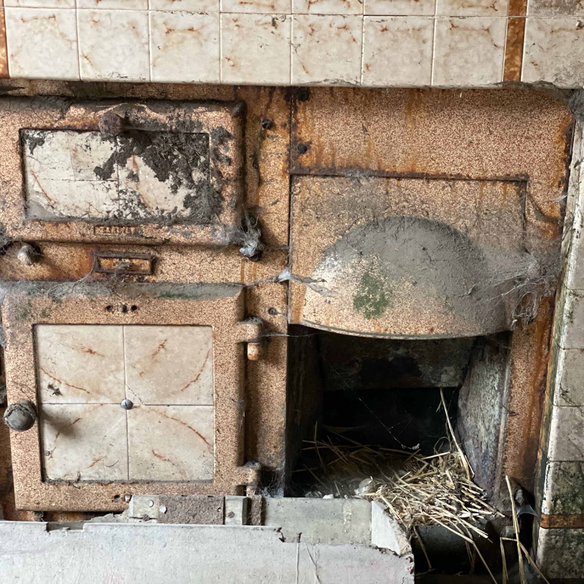 Vintage cast iron range or cooker with ceramic tile inserts in kitchen wall.
